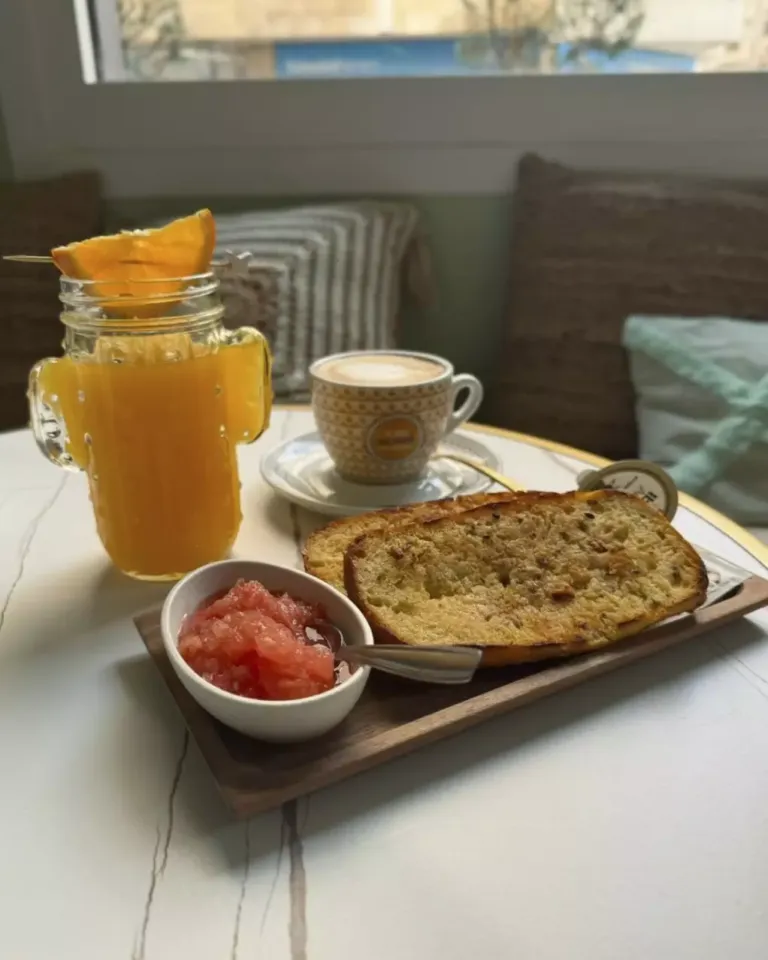 Desayuno compuesto por: tostadas con tomate y aceite, café y zumo de naranja