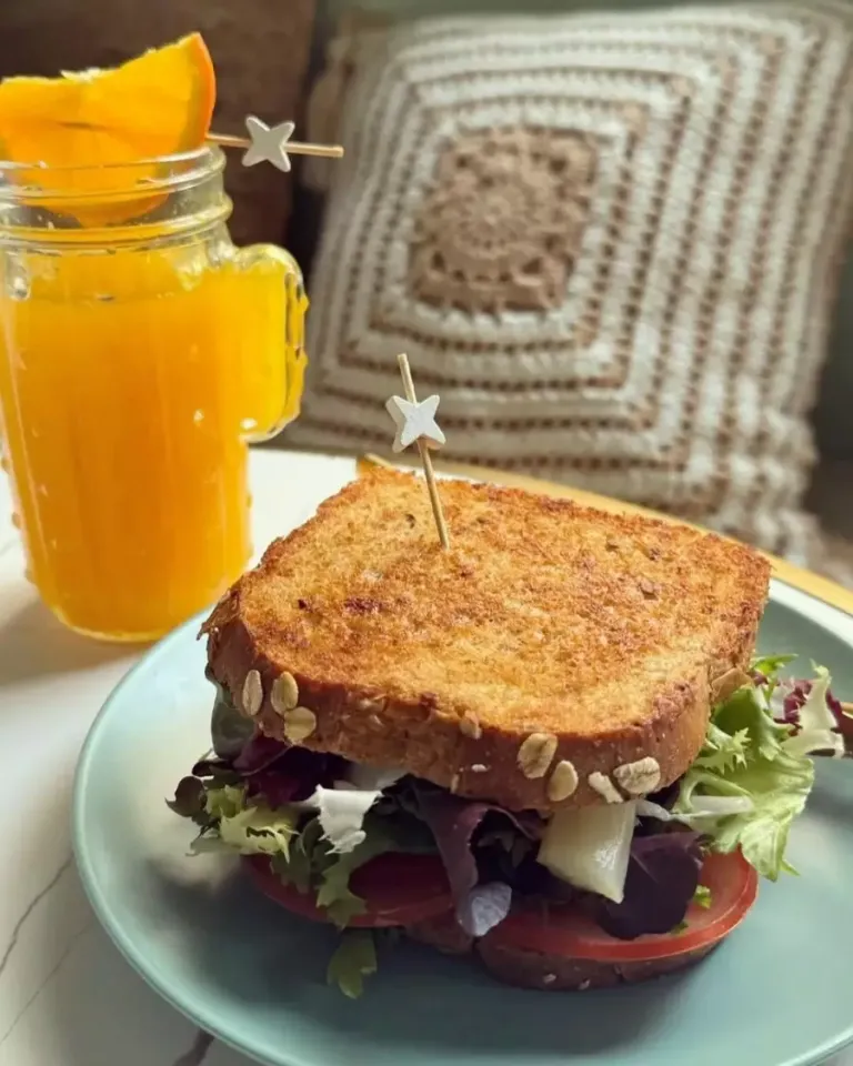 Desayuno compuesto por: sandwich vegetal y zumo de naranja