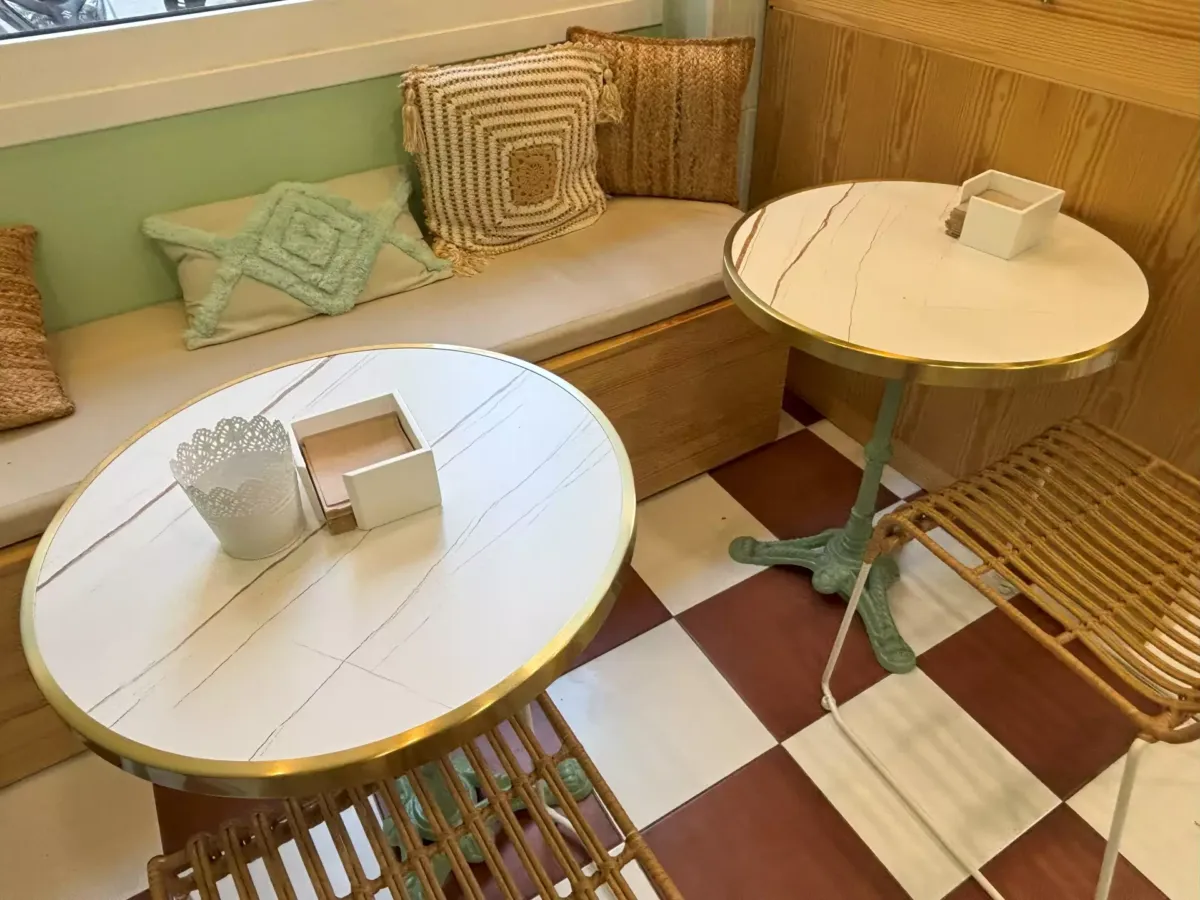 Mesas redondas de la cafetería junto a un banco y sillas