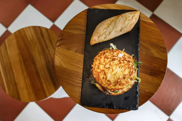 Tortilla de patata rellena junto a aun bollo de pan